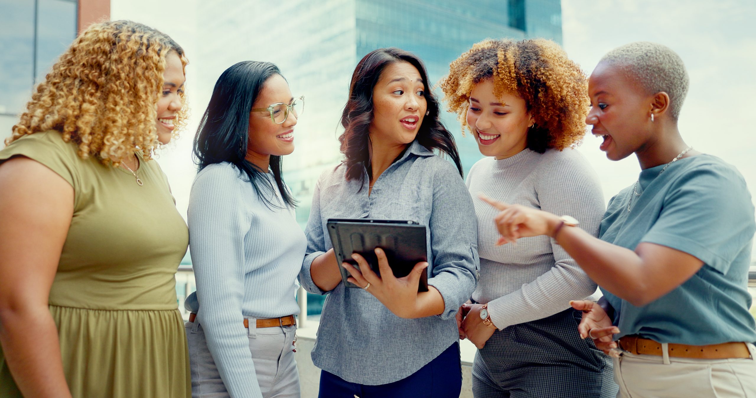 group of women talking at work around an ipad