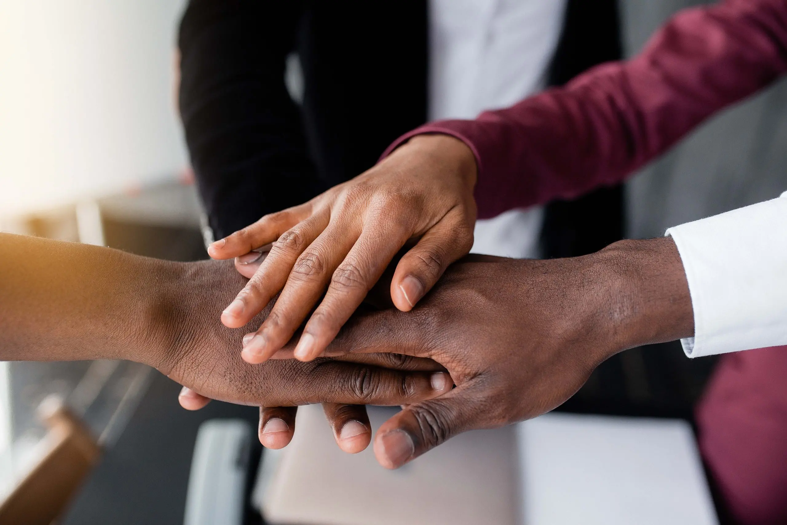 people with their hands in the center hold each other to unite