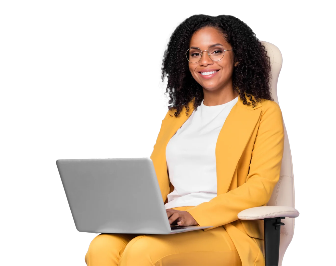 Side view of a woman sitting down in a white chair wearing a yellow suit with a white shirt. She has a gray laptop in her lap and black curly hair. She is smiling at the camera.